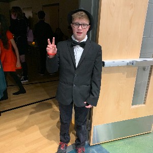 Male student poses dressed in suit for dance.