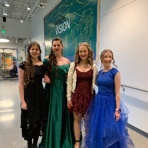 Four students in dresses are ready to enter the school gym.