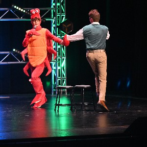 Student dressed as a crab, doing the do-si-do on stage with another singer.