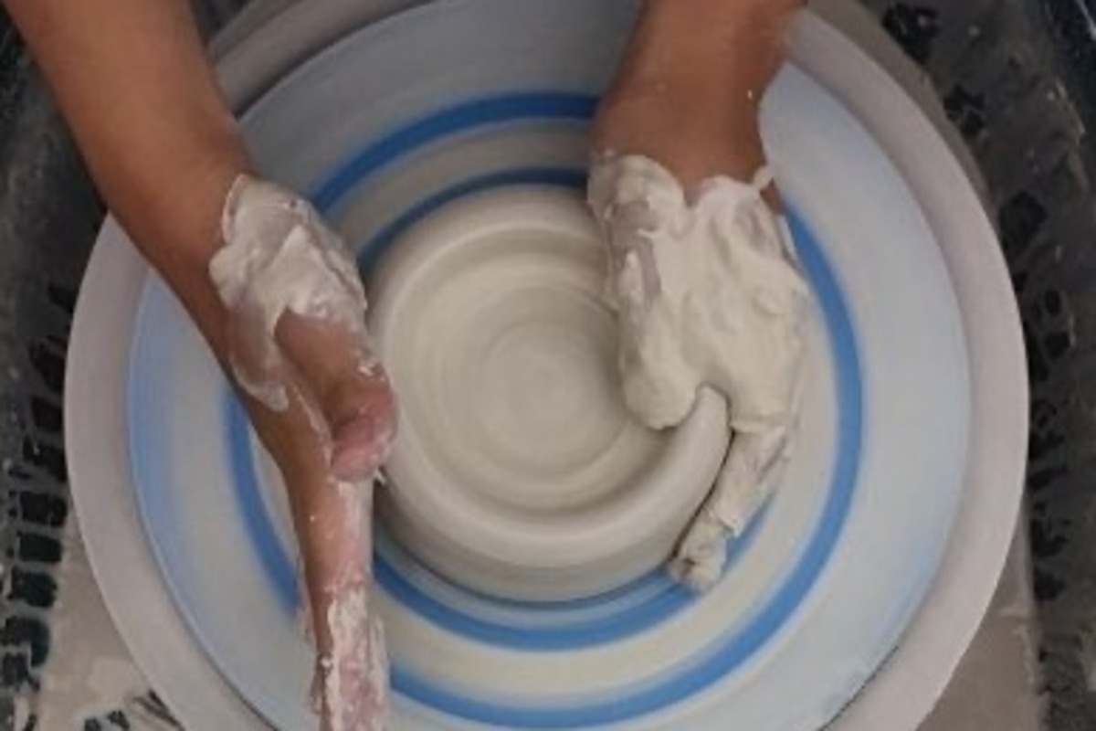 A PCHS student forms a ceramic piece on a pottery wheel.