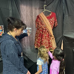 Students and a teacher look at a traditional Indian dress.