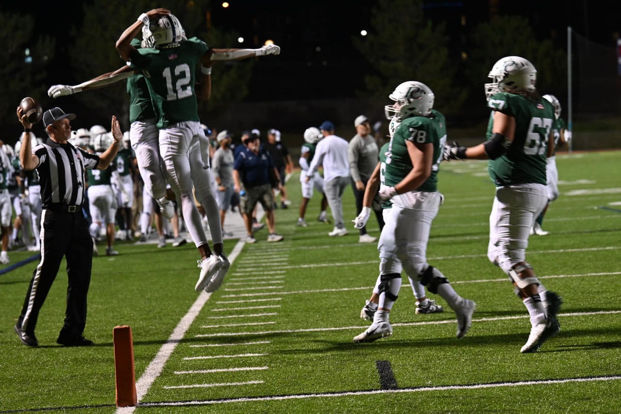 Two football players chest-bump in celebration of a touch down