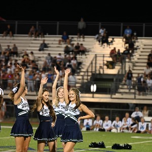 Cheerleaders waiving to the crowd after finishing a performance at halftime.