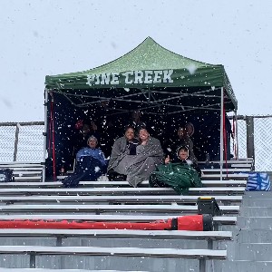 Fans sitting under a Pine Creek tent on the bleachers