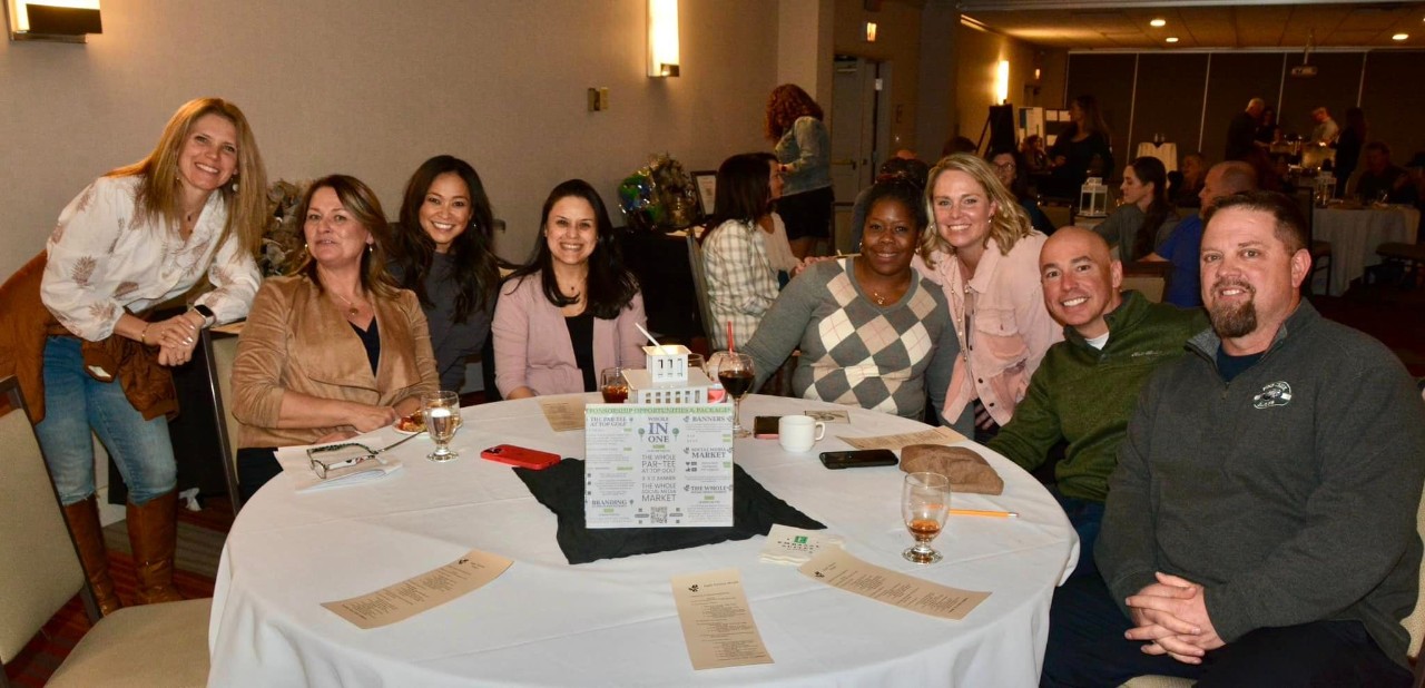 Parents, seated at a table, pose for a photo