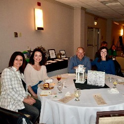 Participants, seated at a table, smile for the camera