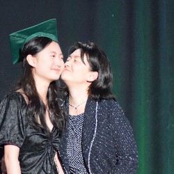 Mom gives graduate a kiss on the cheek