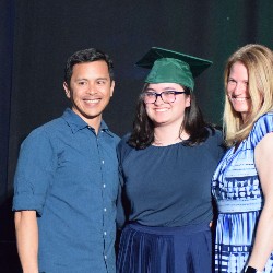 Graduate poses with her parents at the Senior Capping Ceremony