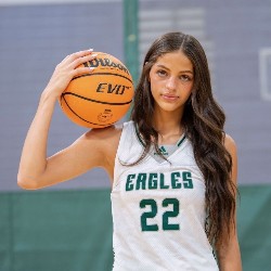 Athlete poses for the camera with basketball on her shoulder