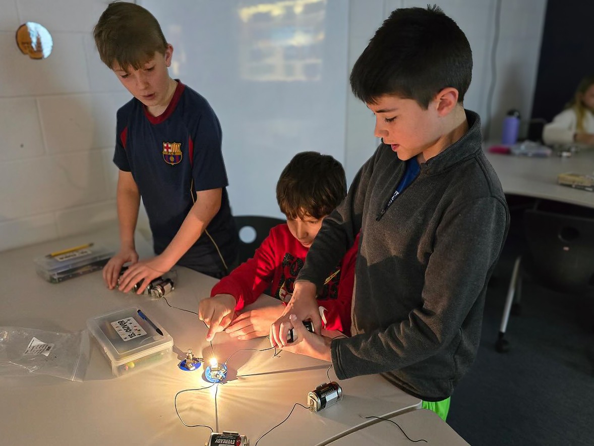 students learning about electricity with batteries and lightbulbs