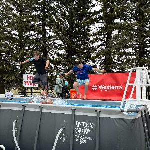 Two boys jumping into an outdoor pool.