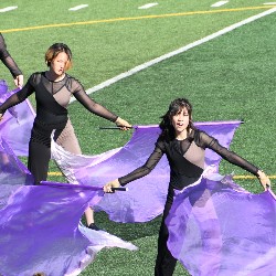 Members of the Color Guard performing with purple flags at the Harrison Marching Band Festival