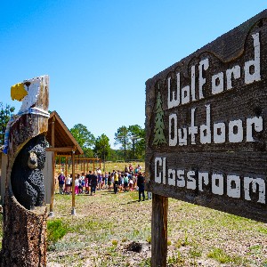 A sign that reads Wolford Outdoor Classroom with students in the background