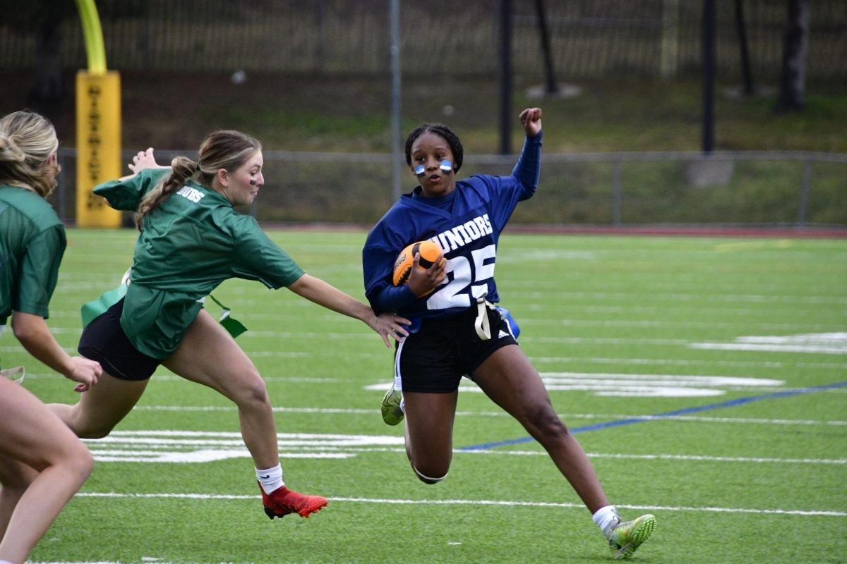 Kaya Burke-Perryman (11) avoids the flag grab by Madison Weiner (12) at the homecoming powder puff game on September 11.