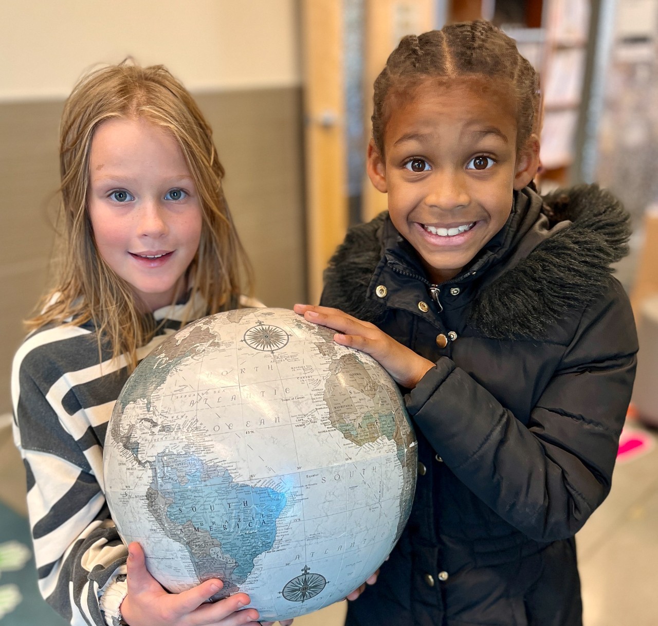 two students holding a globe