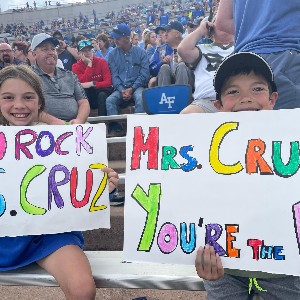 Students smile with posters for their teacher Melanie Cruz