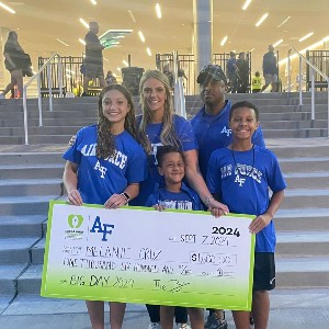 Melanie Cruz, Douglass Valley Elementary School teacher smiles for a photo with her family and a large check