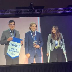 Kate, Cole, and John onstage with tie 1st place trophy