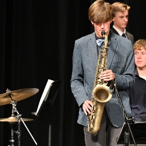 Student in gray suit playing saxophone