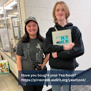 Students with cameras holding a yearbook