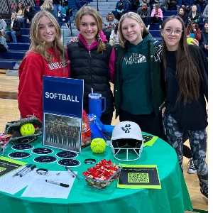 Girls standing in front of a table labeled, "Softball."