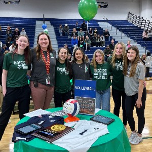 Group standing in front of a table with a volleyball