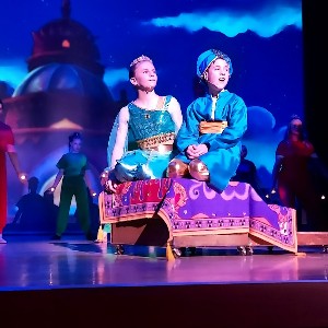 Students performing on stage, riding a magic carpet.