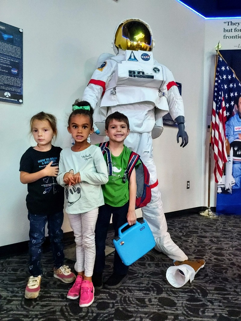 Students standing in front of an astronaut suit