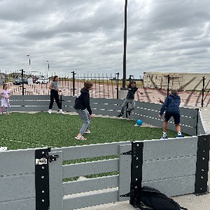 VMS students play an outdoor ball game in an enclosed pen.