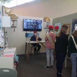 Students in line to talk to a boy sitting at the table