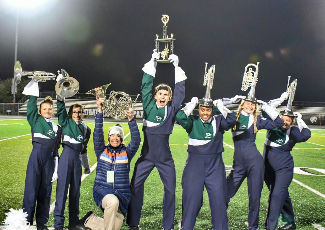 Students holding instruments over heads