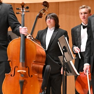 Students standing after a performance holding stringed instruments 