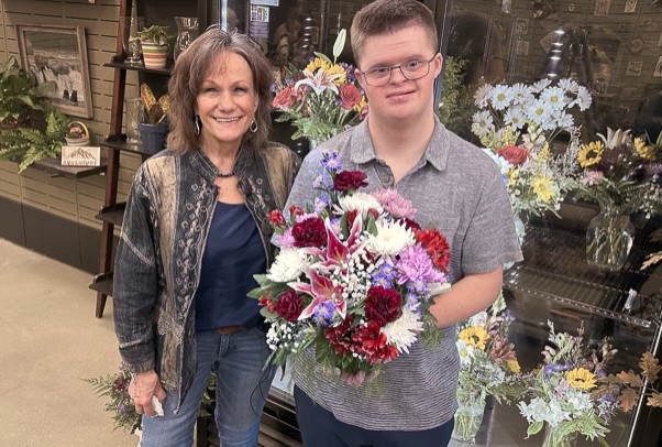 Quentin Avinger holding a bouquet of flowers with DeNyse White, Dandelion Chapel Hills owner.