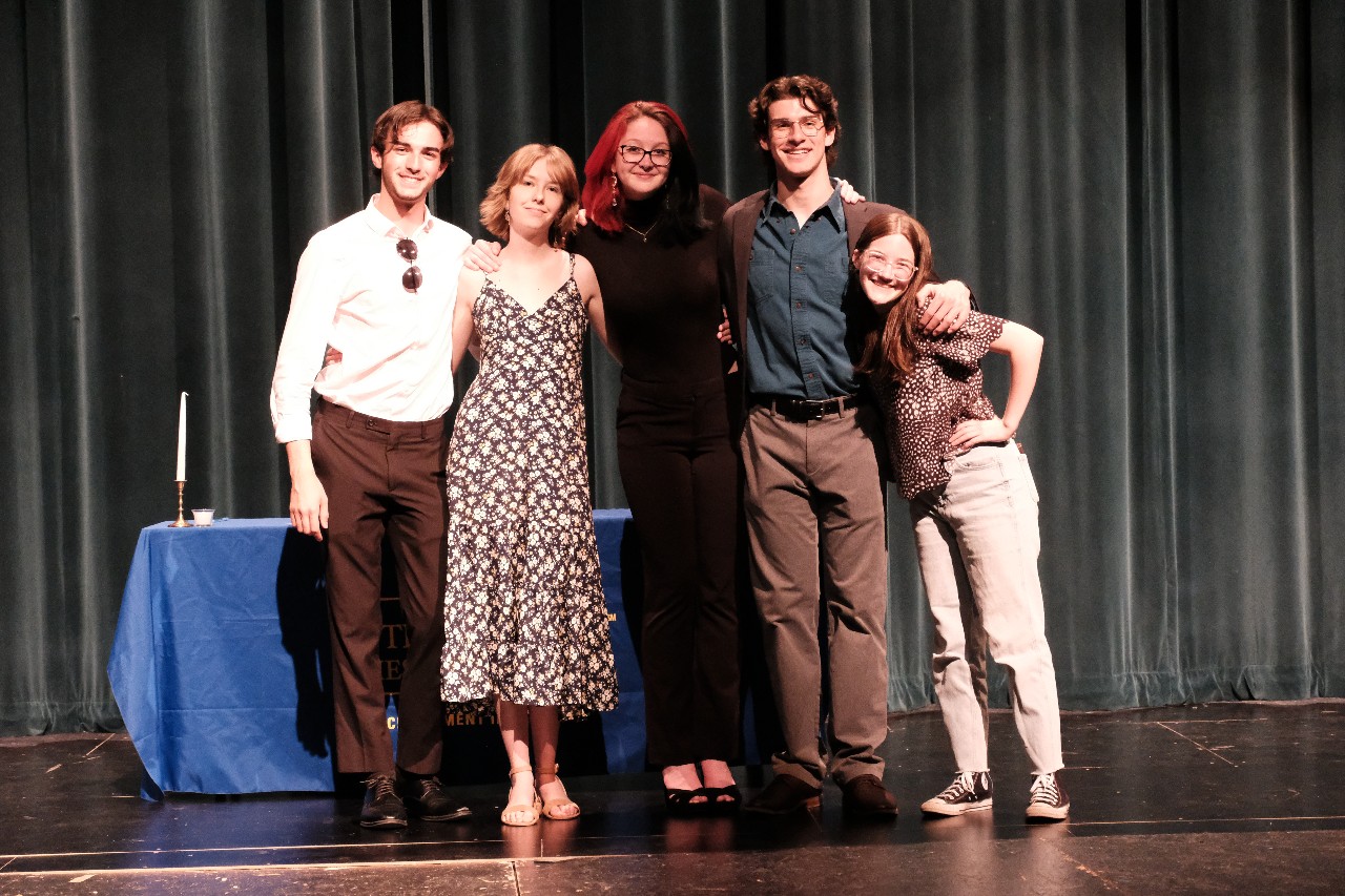 Students posing on stage with linked arms