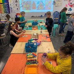 Students creating houses from popsicle sticks and glue