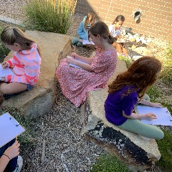 Students sitting outside and drawing.