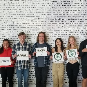 AVID students holding signs with the logo of the college they will attend in the fall, part 1