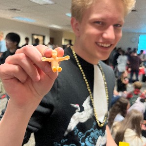 Student holding miniature plastic baby he found in a King Cake