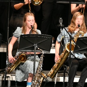 Students playing saxophones while seated