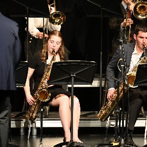 One student playing an alto saxophone, another playing a baritone saxophone