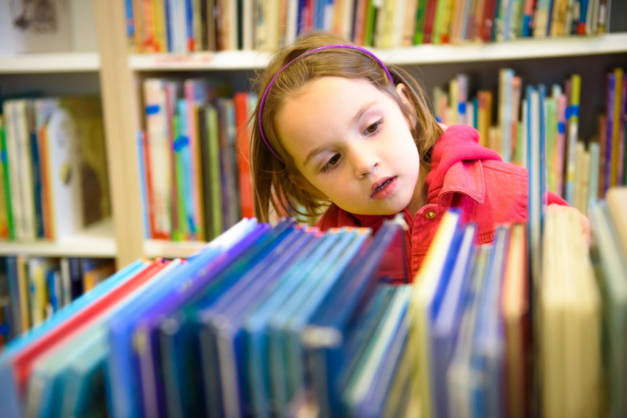 A child checking out books at a library