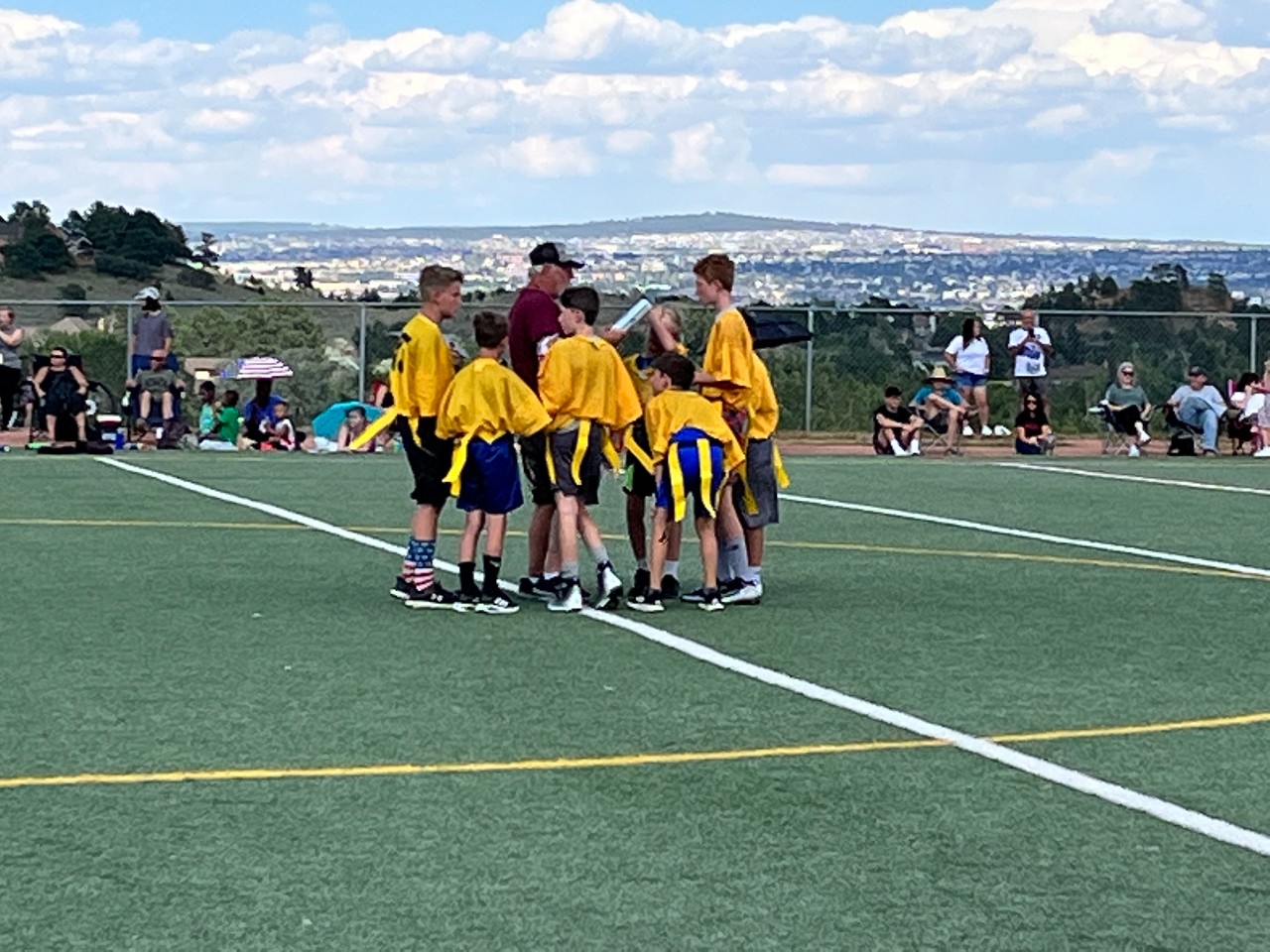 Flag football players huddle around their coach between plays.