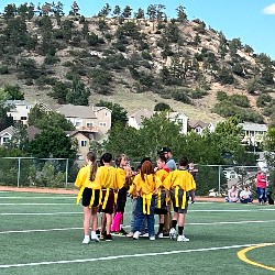 Flag football students huddle around their coach between plays.