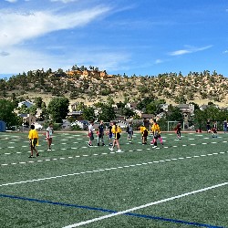 Offensive and defensive students line up at the line of scrimmage at an outdoor flag football game.