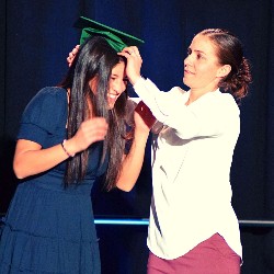 Coach Jubic placing graduation cap on a Senior's head