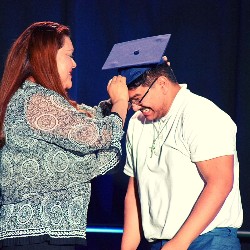 Mother placing graduation cap on son's head