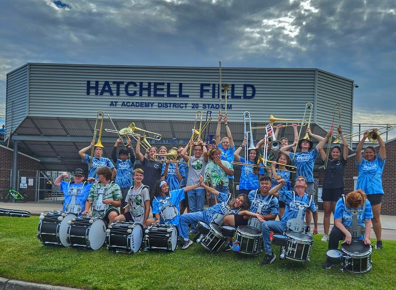 Musicians pose for a "silly" photo while holding their trombones and drums in front of Hatchell Field