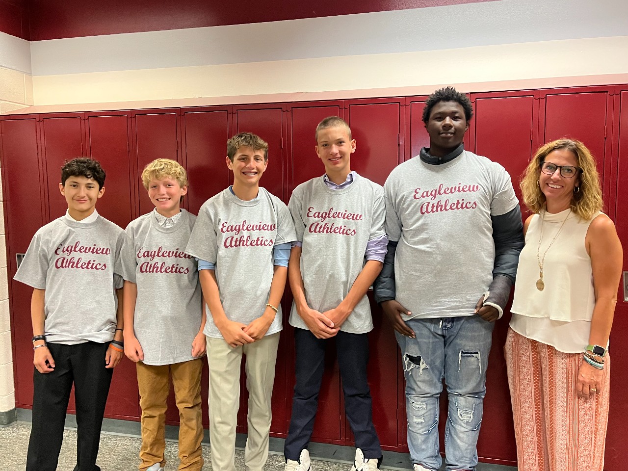 Students wearing the Eagleview Athletics t-shirts stand with Mrs. White in front of lockers.