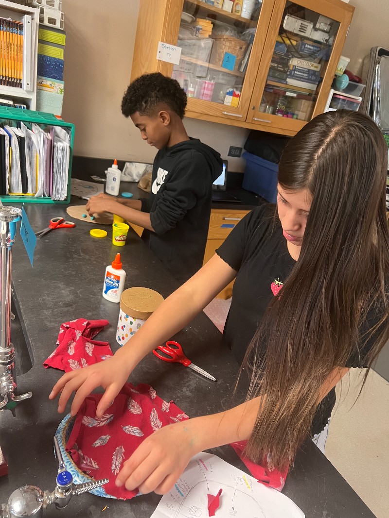 Two students work at a lab table in their science class; they are making 3D representations of cells.