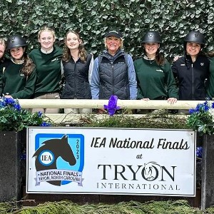 Team posing with sign that says "IEA National Finals at TRYON International"